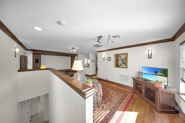 living room with light hardwood / wood-style flooring, ornamental molding, and a textured ceiling