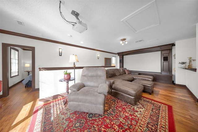 cinema room with crown molding, wood-type flooring, and a textured ceiling