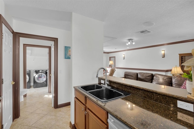 kitchen with sink, separate washer and dryer, light tile patterned floors, ornamental molding, and dark stone counters