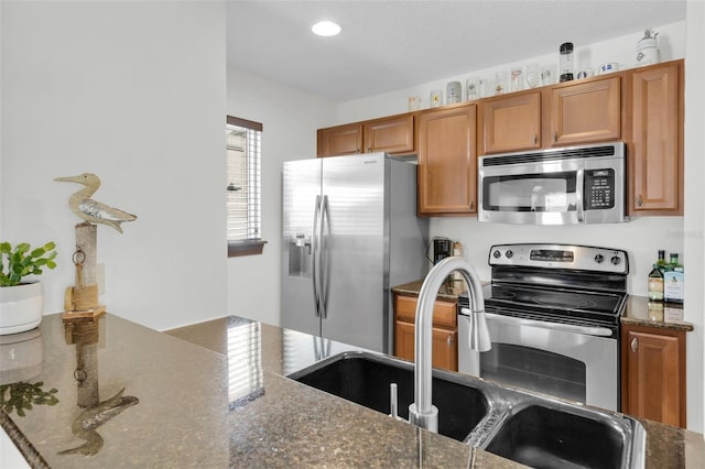 kitchen with appliances with stainless steel finishes, sink, and dark stone countertops