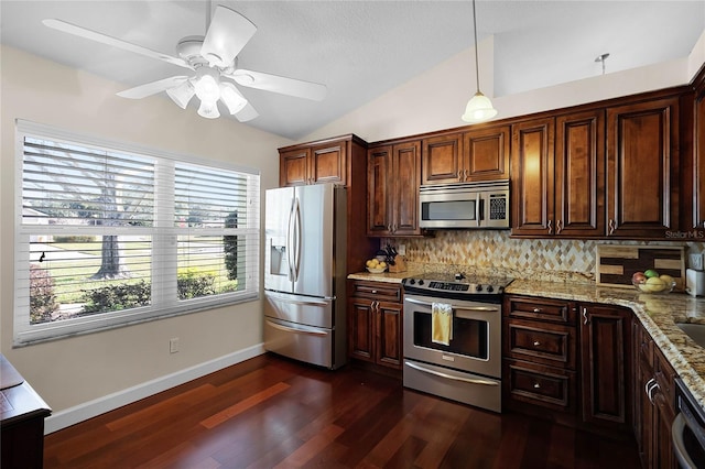 kitchen featuring dark wood-type flooring, light stone counters, vaulted ceiling, hanging light fixtures, and stainless steel appliances