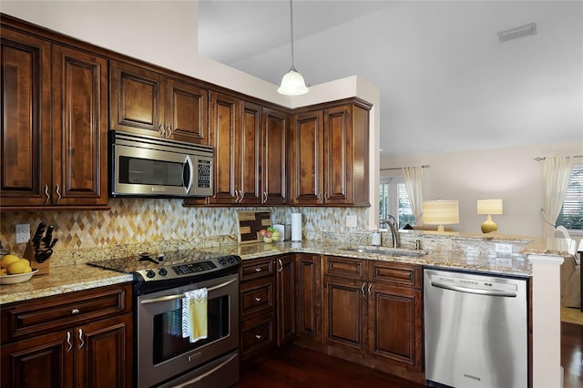 kitchen featuring sink, stainless steel appliances, light stone counters, decorative light fixtures, and kitchen peninsula