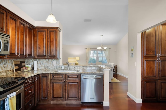 kitchen with stainless steel appliances, light stone countertops, sink, and decorative light fixtures