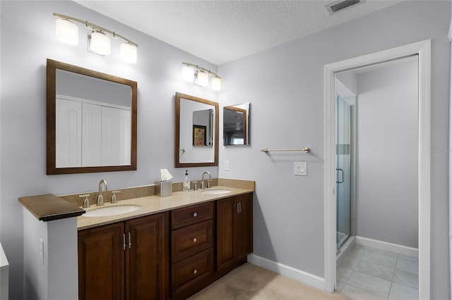 bathroom featuring walk in shower, vanity, tile patterned flooring, and a textured ceiling