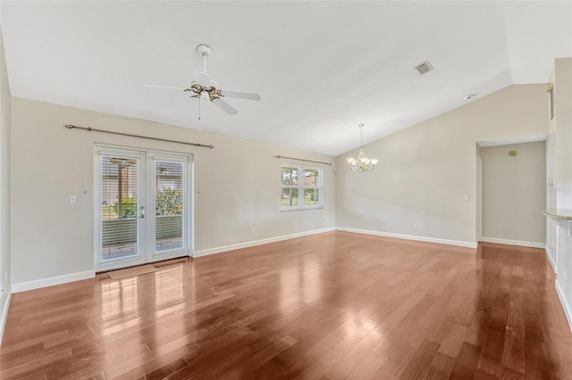 empty room with wood finished floors, ceiling fan with notable chandelier, lofted ceiling, and visible vents