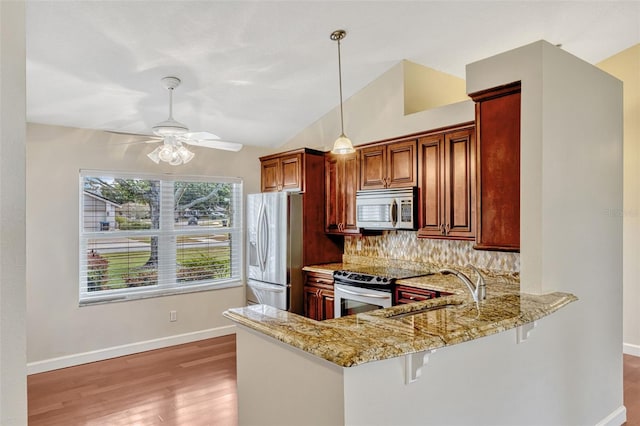 kitchen featuring light stone counters, backsplash, stainless steel appliances, and light wood-style flooring