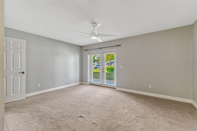 carpeted spare room featuring baseboards and ceiling fan