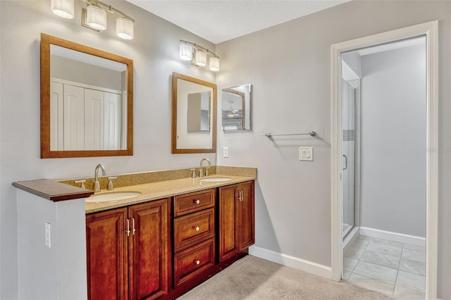 full bath featuring a sink, baseboards, a stall shower, and double vanity
