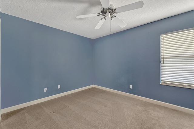 empty room with baseboards, a ceiling fan, a textured ceiling, and carpet
