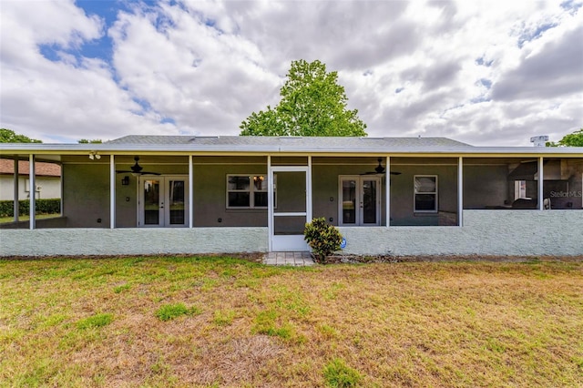 rear view of property featuring a lawn, ceiling fan, and french doors