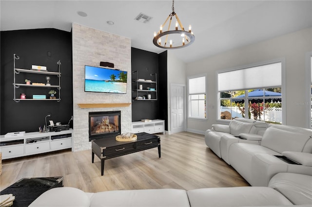 living room featuring vaulted ceiling, a large fireplace, a notable chandelier, light wood-type flooring, and built in shelves