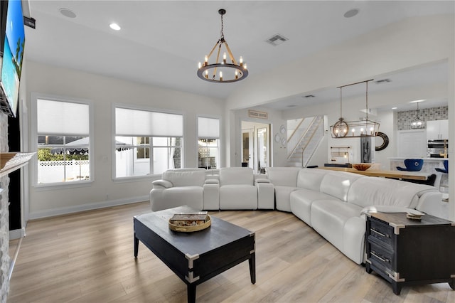 living room with a chandelier, vaulted ceiling, and light hardwood / wood-style flooring