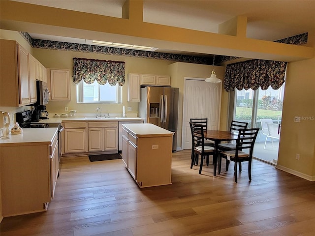 kitchen with appliances with stainless steel finishes, a center island, hanging light fixtures, and a wealth of natural light