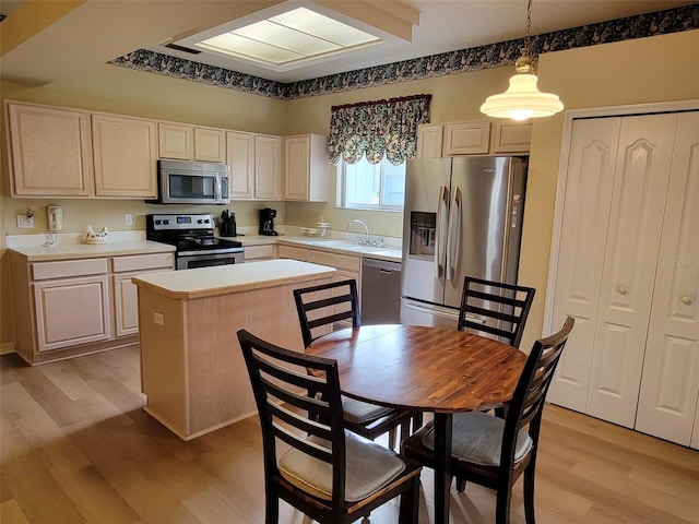 kitchen with sink, a center island, light hardwood / wood-style flooring, appliances with stainless steel finishes, and pendant lighting