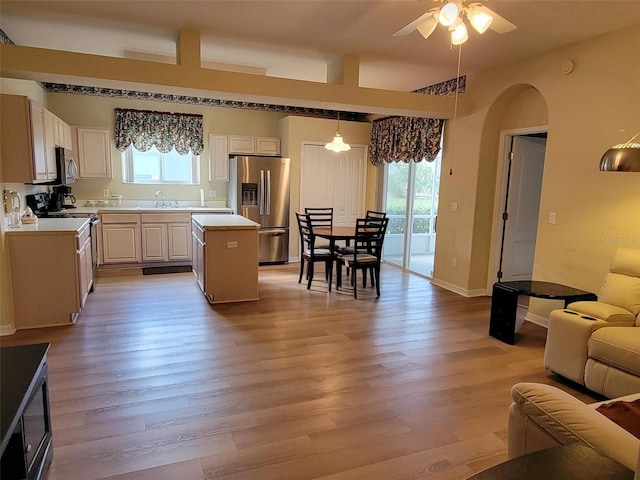 kitchen featuring stainless steel appliances, a kitchen island, plenty of natural light, and decorative light fixtures