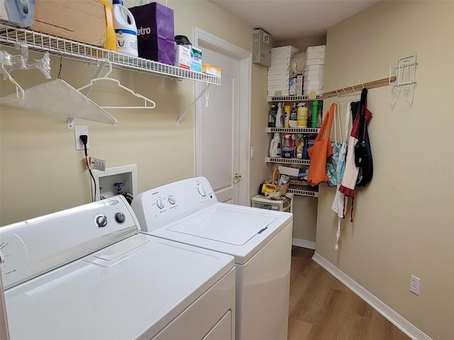 laundry room with washing machine and dryer and light hardwood / wood-style flooring