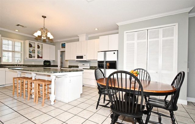 kitchen with white cabinetry, a kitchen island, ornamental molding, and white appliances