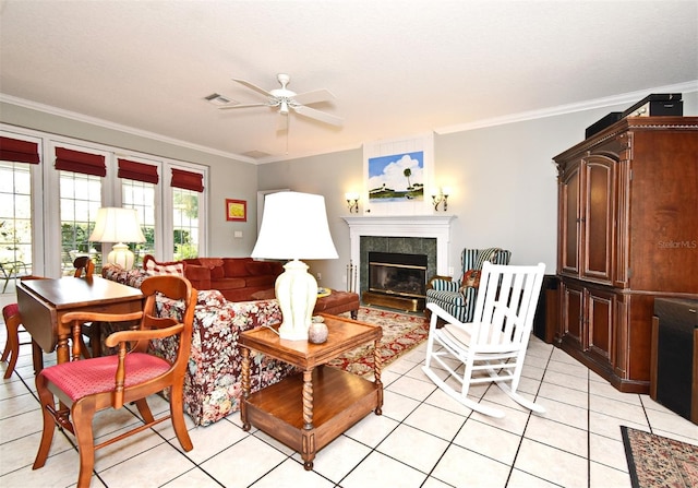 tiled living room with a tiled fireplace, crown molding, and ceiling fan