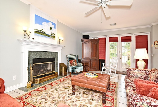 tiled living room featuring a fireplace, ornamental molding, french doors, and ceiling fan