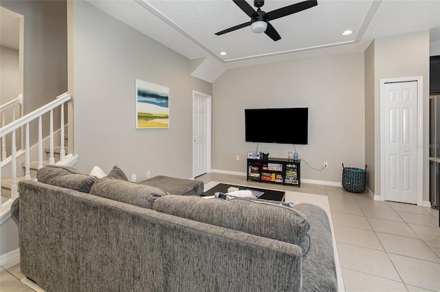 living room with ceiling fan, lofted ceiling, a textured ceiling, and light tile patterned floors