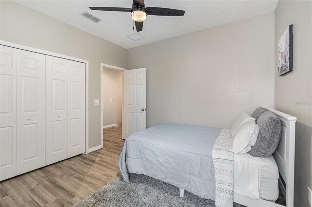 bedroom featuring ceiling fan, a textured ceiling, a closet, and light hardwood / wood-style flooring