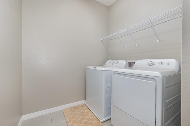 clothes washing area featuring light tile patterned floors and washer and dryer