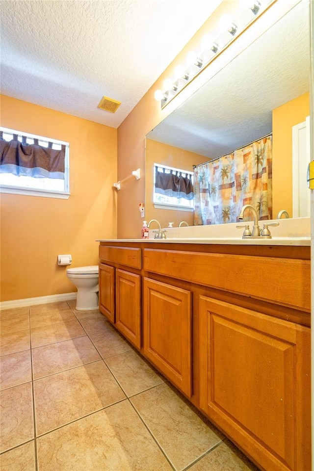 bathroom featuring double vanity, visible vents, toilet, tile patterned flooring, and a textured ceiling