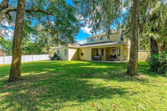 back of property featuring a fenced backyard, a gate, a yard, a patio area, and stucco siding