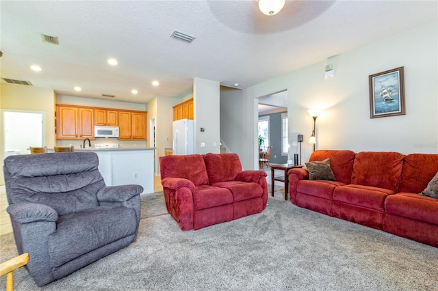 living area featuring recessed lighting, visible vents, and a textured ceiling