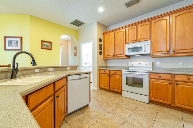 kitchen with light countertops, white appliances, a sink, and visible vents