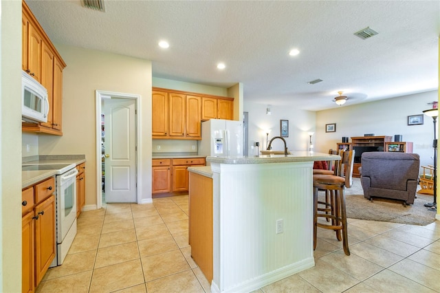 kitchen with light countertops, visible vents, open floor plan, white appliances, and a kitchen breakfast bar