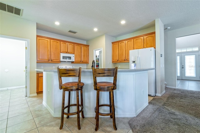 kitchen featuring white appliances, a center island with sink, visible vents, light countertops, and french doors