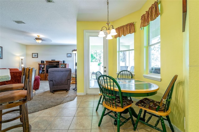 dining space featuring visible vents, a textured ceiling, an inviting chandelier, and light tile patterned floors