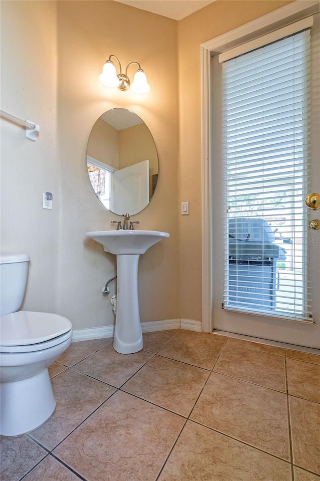 half bathroom featuring toilet, baseboards, and tile patterned floors