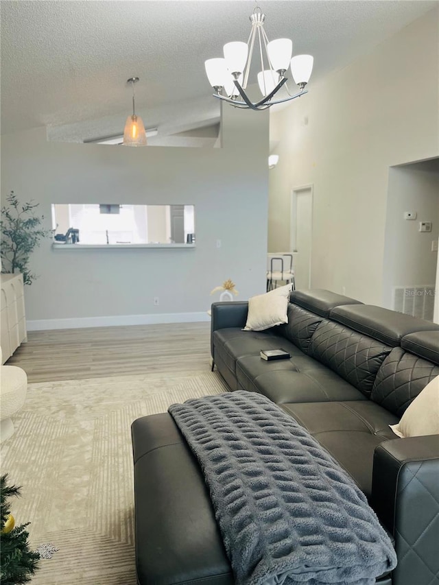 living room with an inviting chandelier, a towering ceiling, a textured ceiling, and light wood-type flooring