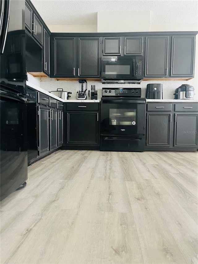 kitchen featuring backsplash, a textured ceiling, light hardwood / wood-style flooring, and black appliances