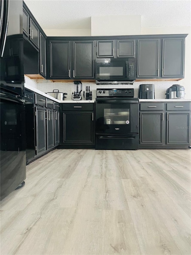 kitchen with backsplash, light wood-type flooring, a textured ceiling, and black appliances