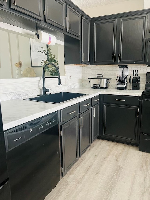 kitchen featuring sink, backsplash, light hardwood / wood-style flooring, and black appliances