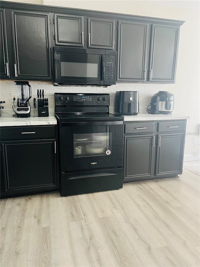 kitchen featuring backsplash, light hardwood / wood-style flooring, and black appliances