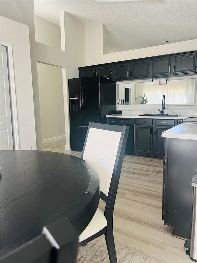 kitchen featuring light wood-type flooring, sink, a high ceiling, and black appliances