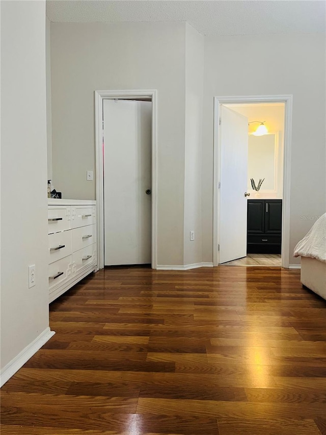 unfurnished bedroom featuring connected bathroom and dark hardwood / wood-style flooring