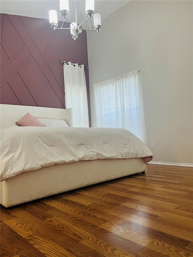 unfurnished bedroom featuring wood-type flooring and a notable chandelier