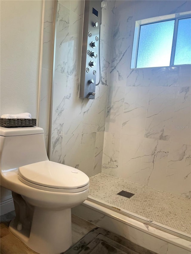 bathroom featuring tiled shower and toilet