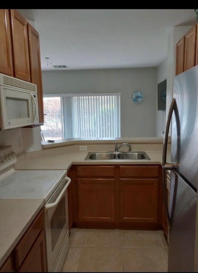 kitchen featuring white appliances, sink, and light tile patterned floors