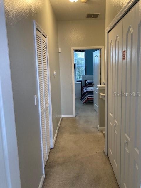 hallway featuring light colored carpet