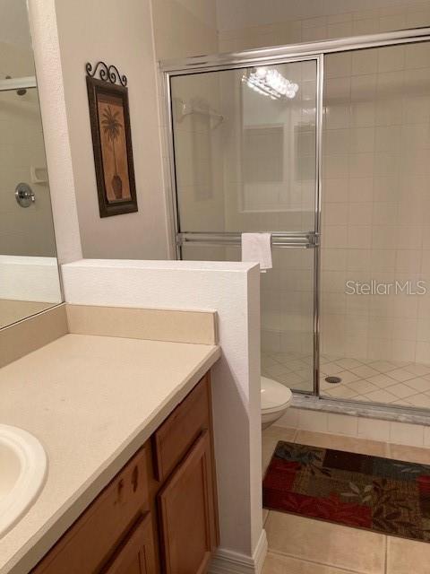 bathroom featuring vanity, tile patterned floors, toilet, and walk in shower