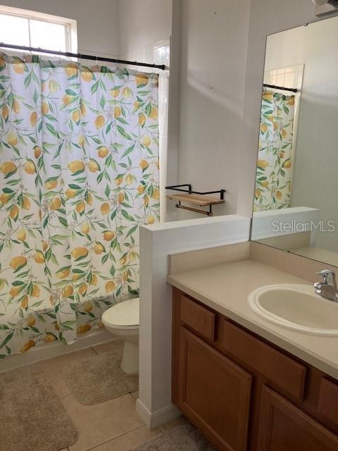 full bathroom featuring toilet, tile patterned floors, vanity, and shower / bathtub combination with curtain