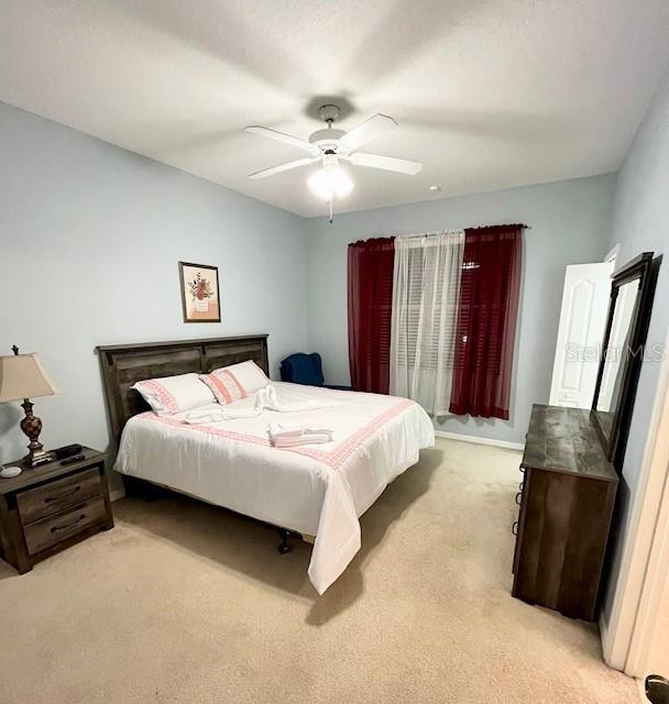 bedroom with ceiling fan and light colored carpet