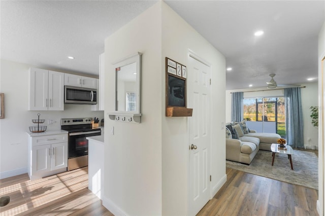 kitchen featuring ceiling fan, stainless steel appliances, light hardwood / wood-style floors, and white cabinets