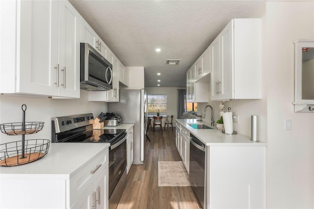 kitchen with dark wood-type flooring, sink, a textured ceiling, stainless steel appliances, and white cabinets